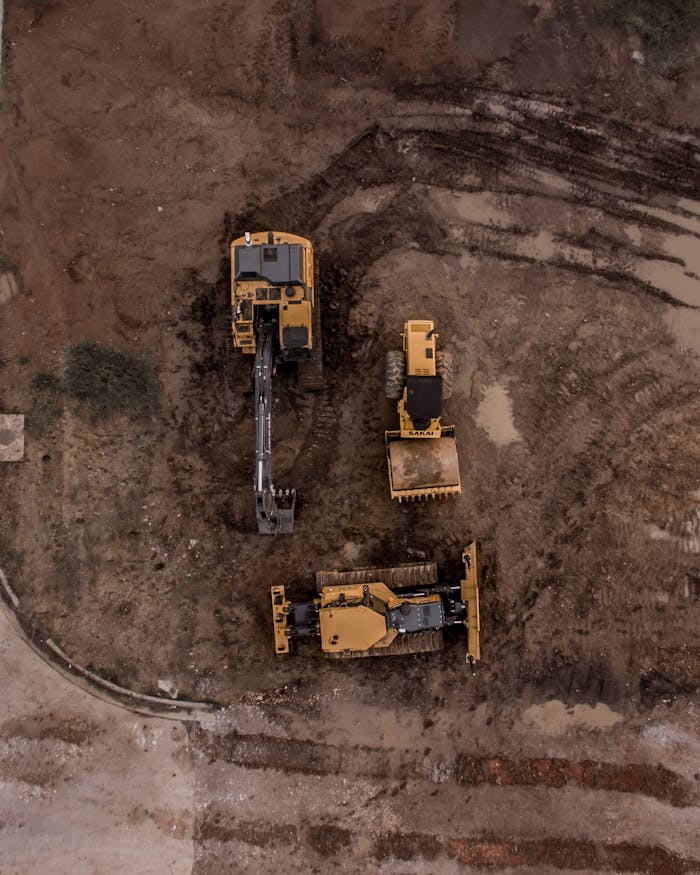 aerial-photo-of-excavator-road-roller-and-bulldozer-1579356 An aerial shot of heavy machinery at a construction site, including excavators and road rollers.